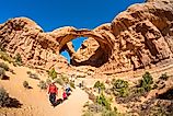 A family of adventurers in Double Arch in Arches National Park, Moab, Utah. Photography by Fotoluminate LLC via Shutterstock 