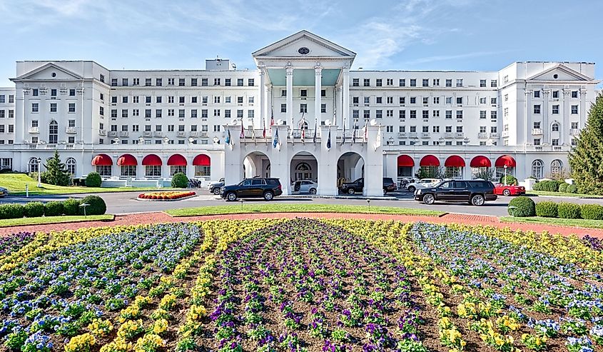 Greenbrier Hotel resort exterior entrance with landscaped flowers, lawn, cars, in West Virginia
