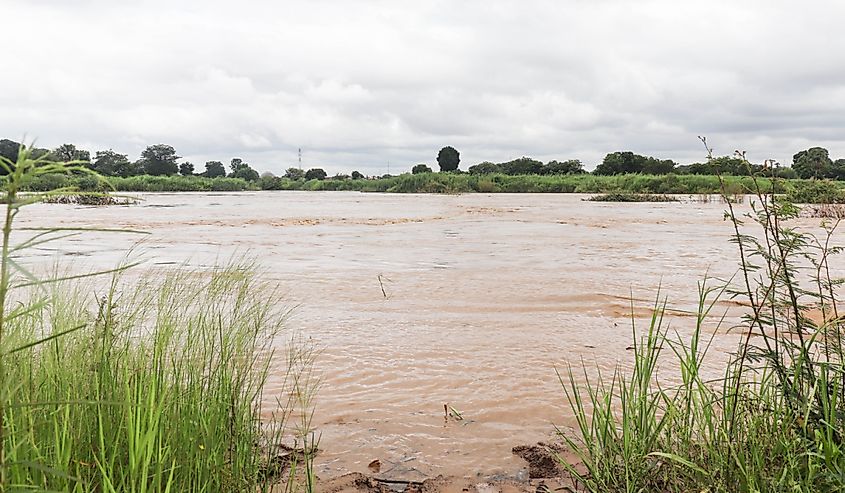 This image features a flowing river with dirty water with a cloudy sky.