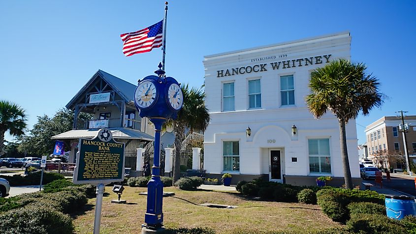 The Hancock Bank of Bay St. Louis, Mississippi, on Main Street, stands out with a big clock and flag.