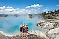 A family of tourists enjoying the view of a geyser in Yellowstone National Park. Wyoming, USA.