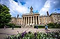 Students and adults walk in front of the Old Main building, on the campus of Penn State University, in State College, Pennsylvania. 