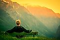 A man sitting alone with the vast mountains in front of him.