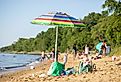 A beach umbrella stands in the sand at Matapeake Clubhouse and Beach on Kent Island, Maryland. Image credit Nicole Glass Photography via Shutterstock. 