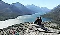 Couple With Elevated View of Town of Waterton, Alberta and a Mountain Lake - Waterton Lakes National Park, Canada.