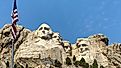 Mount Rushmore with the American flag waving in the foreground.