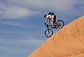 A fearless mountain biker drops down a steep section of Moab's Slickrock Trail, Utah.