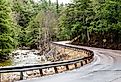 A narrow road curves beside a rushing stream at the eastern edge of the Adirondack Mountains in northeast New York.