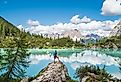 Backpacker with backpack enjoying the turquoise Lago di Sorapiss 1,925m altitude (mountain lake) view as he has mountain walk in Dolomite Mountains, Italy. Active people in nature concept.