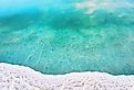 Shore of Dead sea in Ein Bokek, Israel, white salt crystals outside and at the bottom, turquoise clear water.