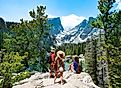 Family standing on top of the mountain enjoying beautiful scenery. Early summer landscape with lake and snow covered mountains.