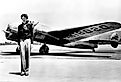 Amelia Earhart standing in front of her Lockheed Electra.