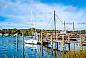 Commercial dock with moored white boat and sailing ship in Mystic, Connecticut.