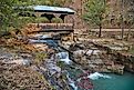 Covered bridge over cascading waterfall in fall in Ponca, Arkansas.