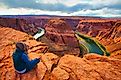 A person meditating in front of the scenic Horseshoe Bend of the Colorado River in Arizona.