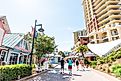 Destin, Florida: City town village Pirate's Alley on Harbor Boardwalk during sunny day in Florida panhandle gulf of mexico, tourists people walking, via krblokhin / iStock.com