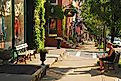 A young woman works on a laptop sitting on a bench in downtown Cold Spring, New York, James Kirkikis / Shutterstock.com