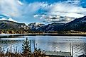 Views of the snow-covered mountain tops of the Rocky Mountains across a still, smooth lake in Grand Lake, Colorado