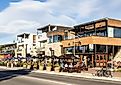 Tourists and locals enjoy a drink on the trendy sidewalk bar and restaurants in Wanaka lakefront in Wanaka, New Zealand. Editorial credit: AsiaTravel / Shutterstock.com