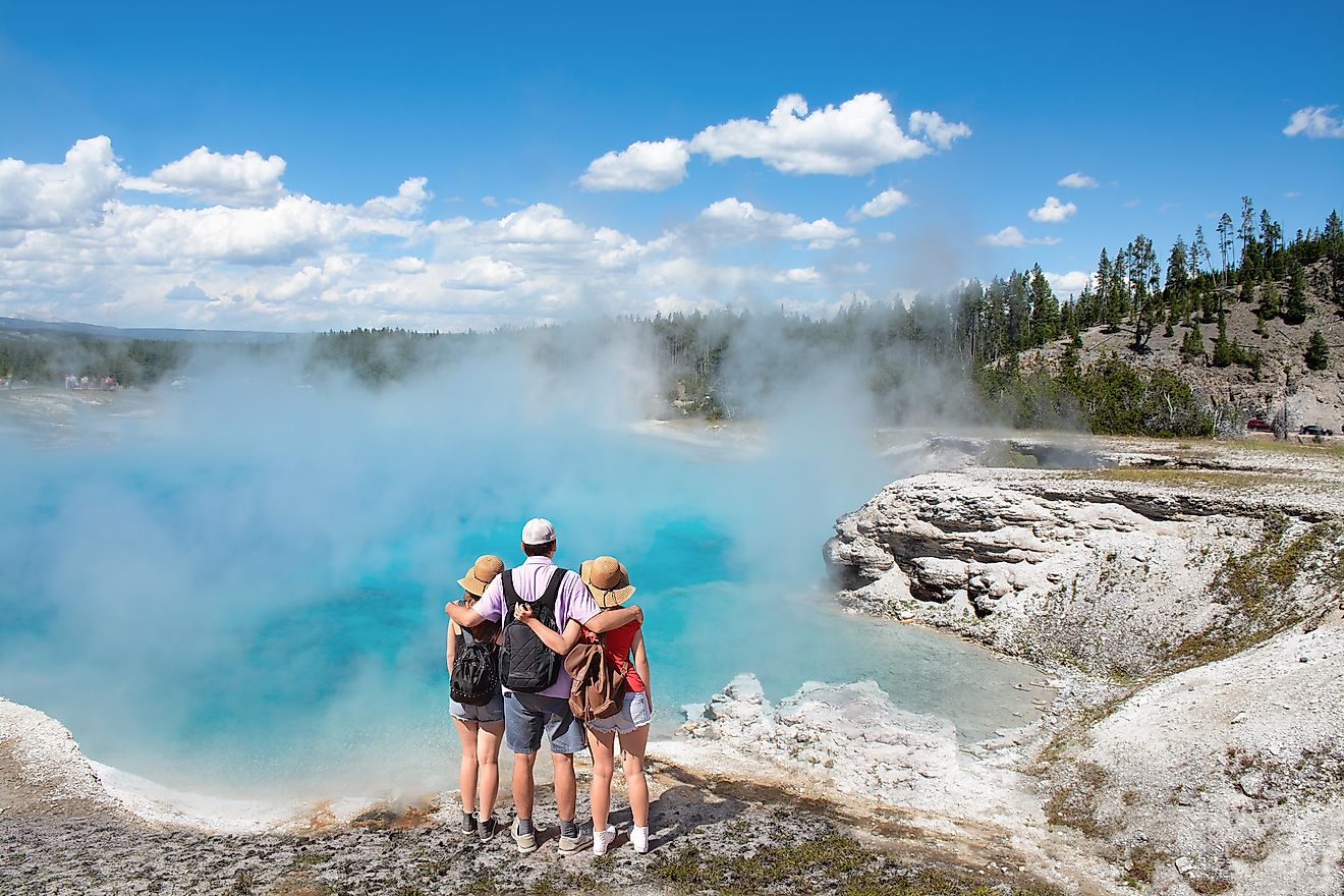 A family of tourists enjoying the view of a geyser in Yellowstone National Park. Wyoming, USA.