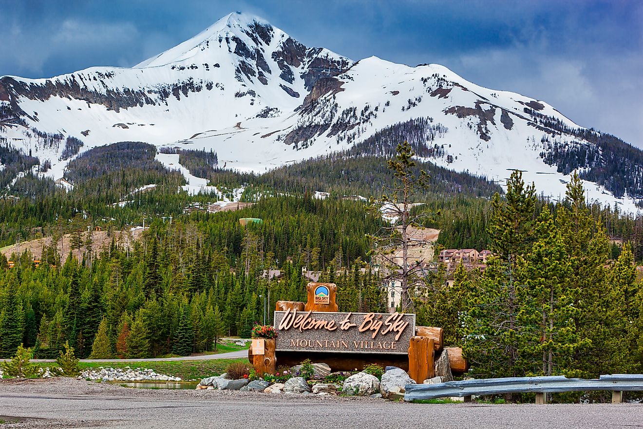 Welcome to Big Sky Mountain Village Signage, dwarfed by the enormity of Lone Mountain full of snow in the Madison Range in the state of Montana. Editorial credit: Zorro Stock Images / Shutterstock.com