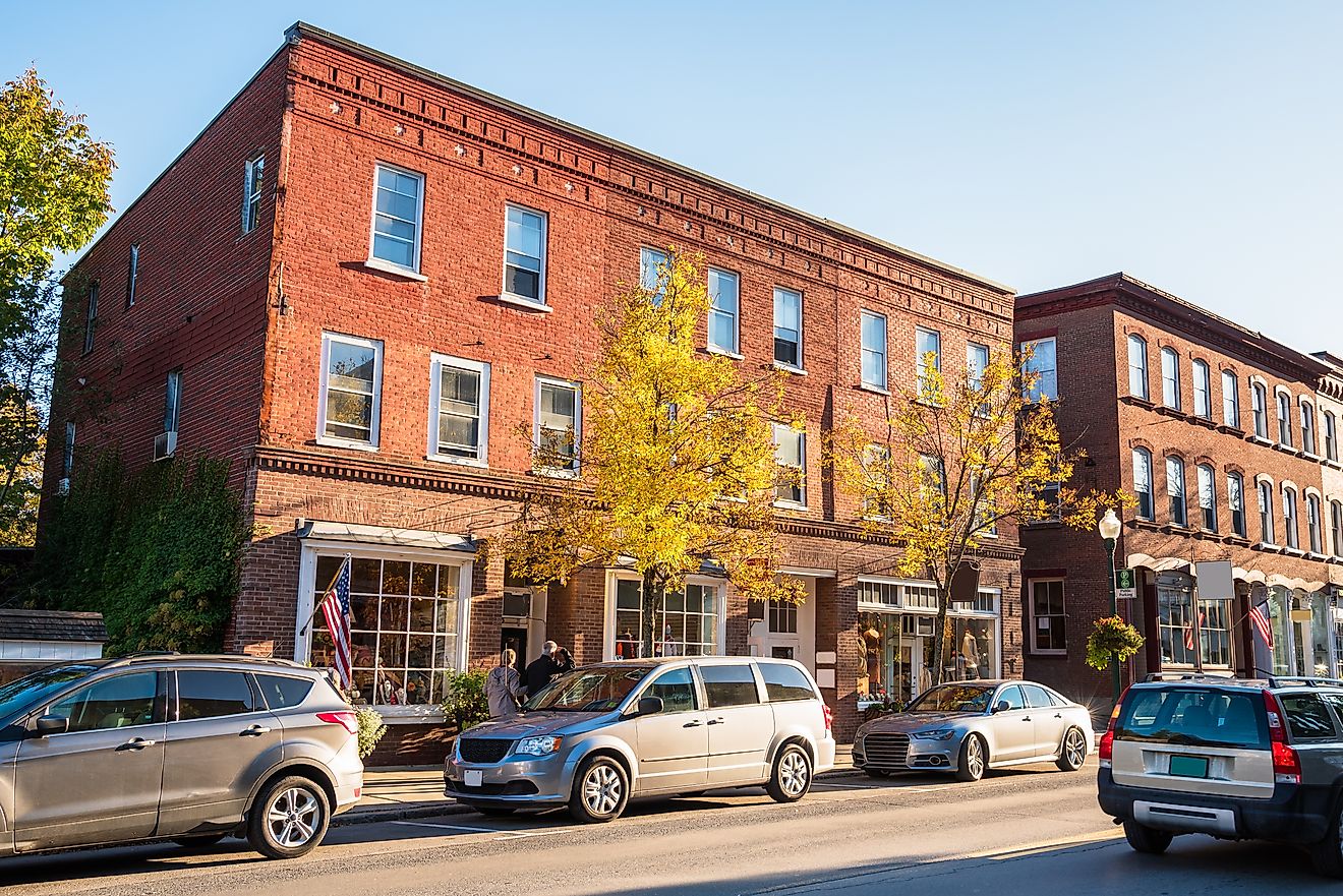Traditional American brick buildings with shops along a busy street at sunset in Woodstock, Vermont, USA.