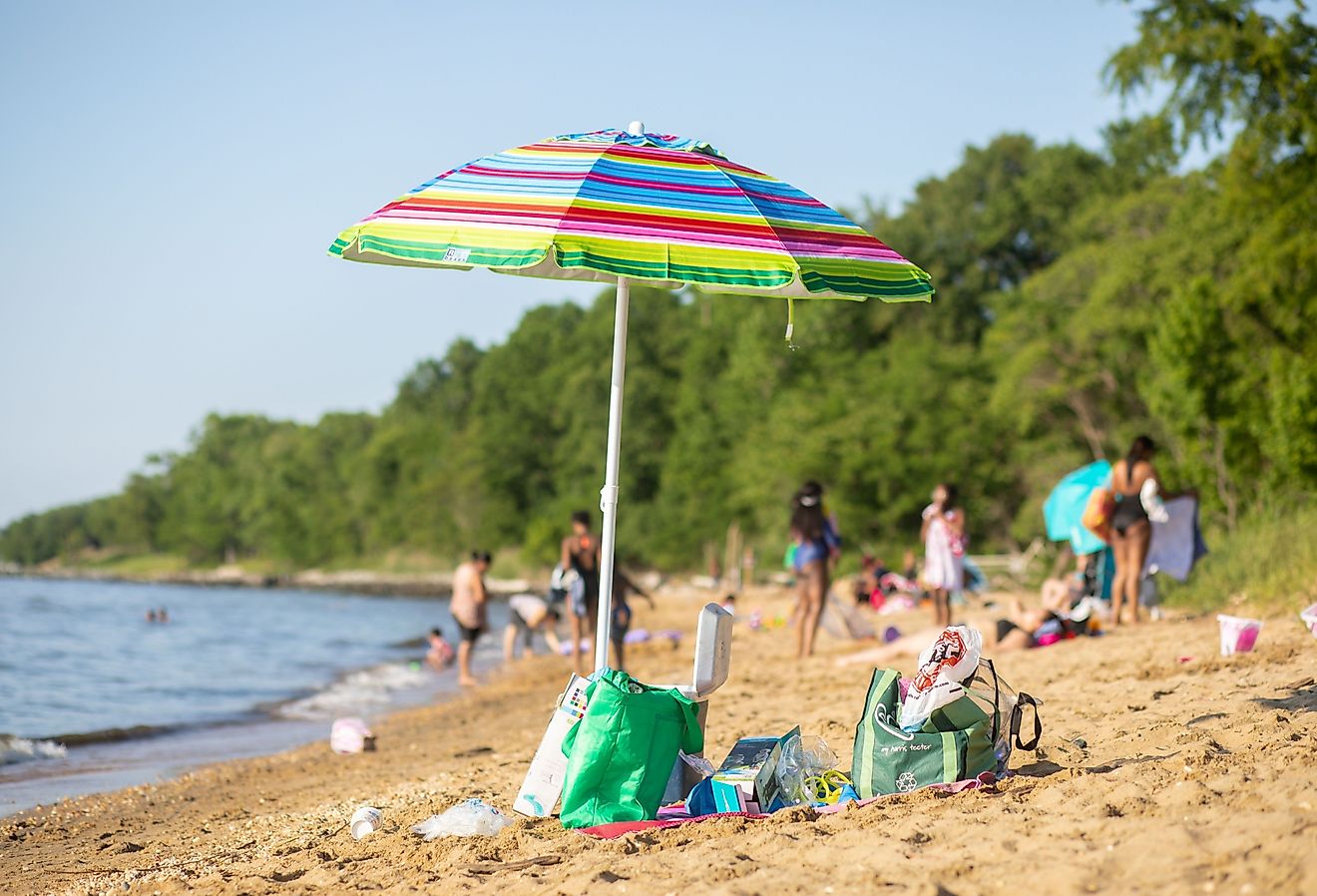A beach umbrella stands in the sand at Matapeake Clubhouse and Beach on Kent Island, Maryland. Image credit Nicole Glass Photography via Shutterstock. 
