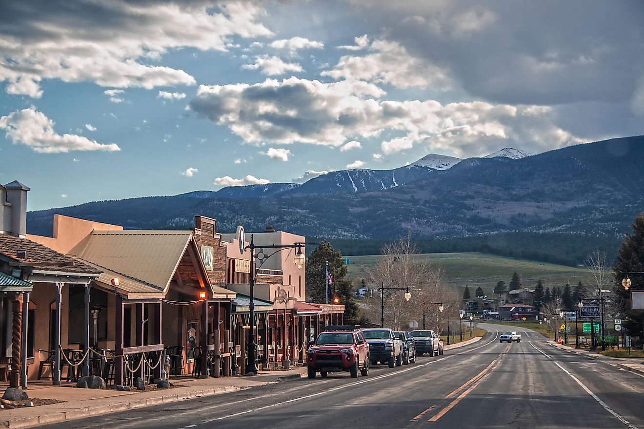 Red River, New Mexico, a small western-style tourist town near the Angel Fire ski resort, with cars parked along the main street and mountains in the background at dusk. Editorial credit: Vineyard Perspective / Shutterstock.com