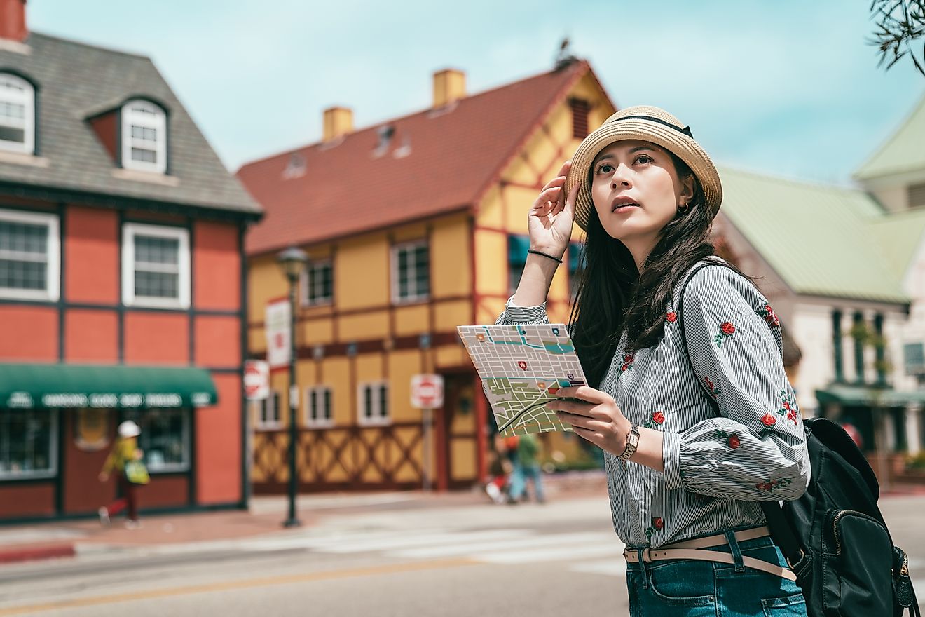 n Asian woman sightseeing with a map in Solvang, California.