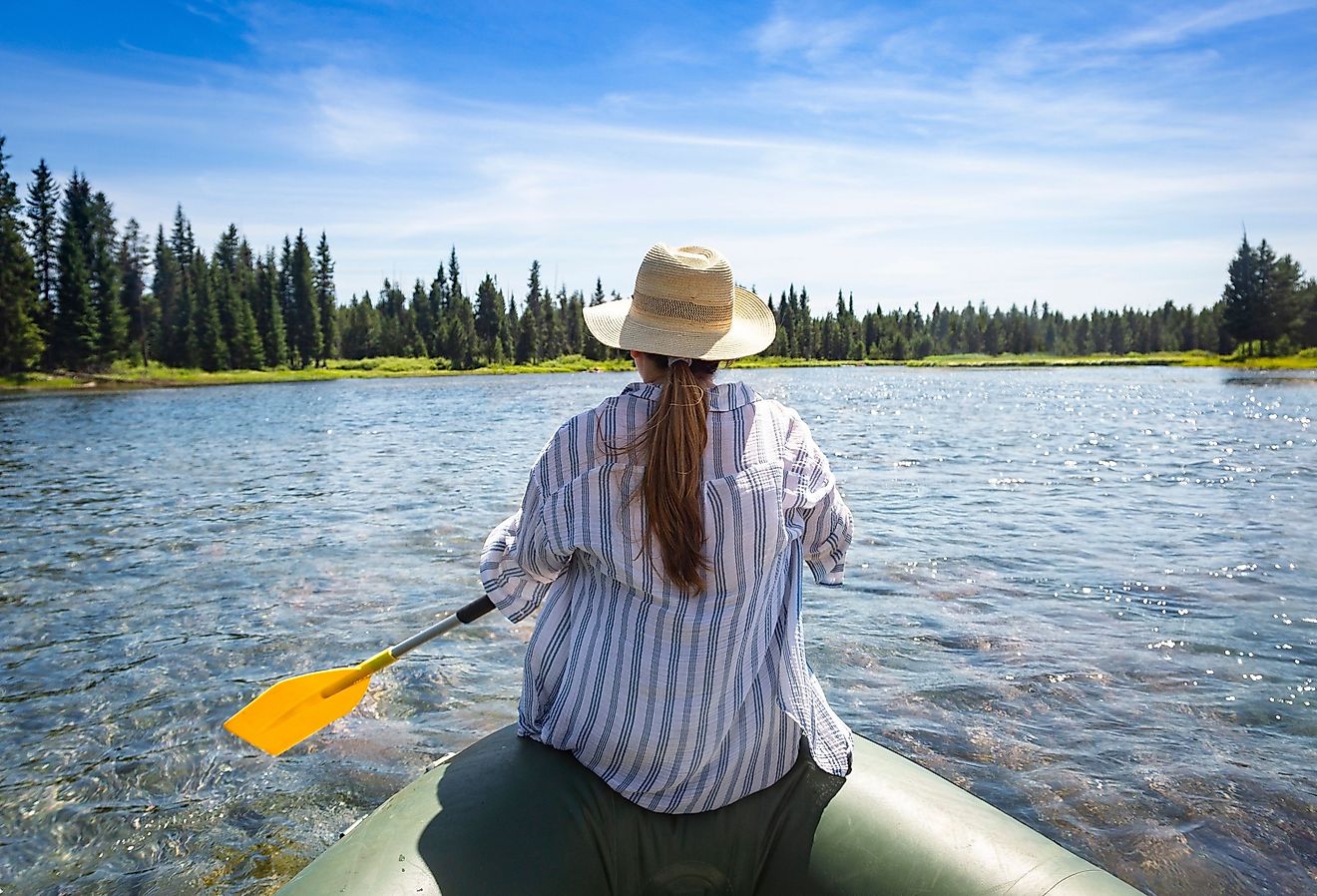 Woman paddling on an inflatable raft while floating the Snake River in Island Park, Idaho.