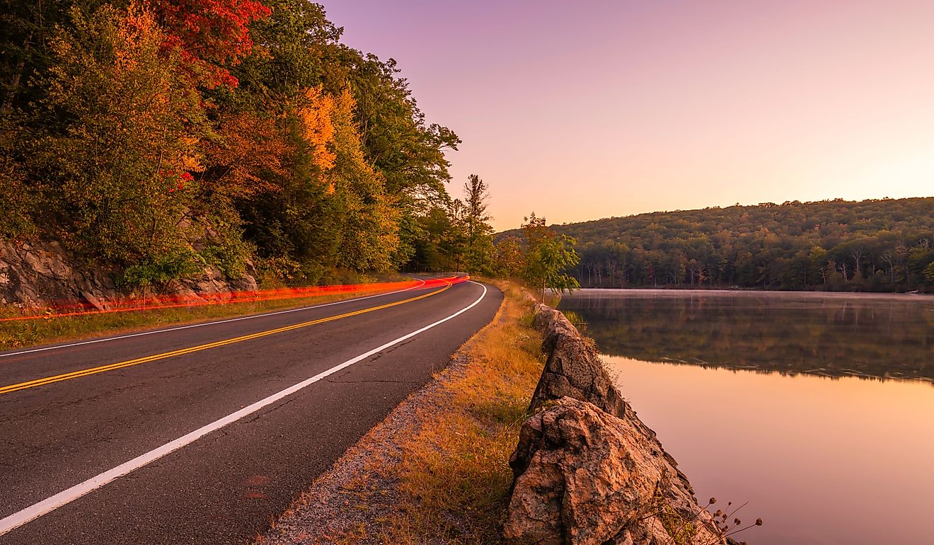 Morning sky over the road passing through the lake and trees at Harriman Park in New York.