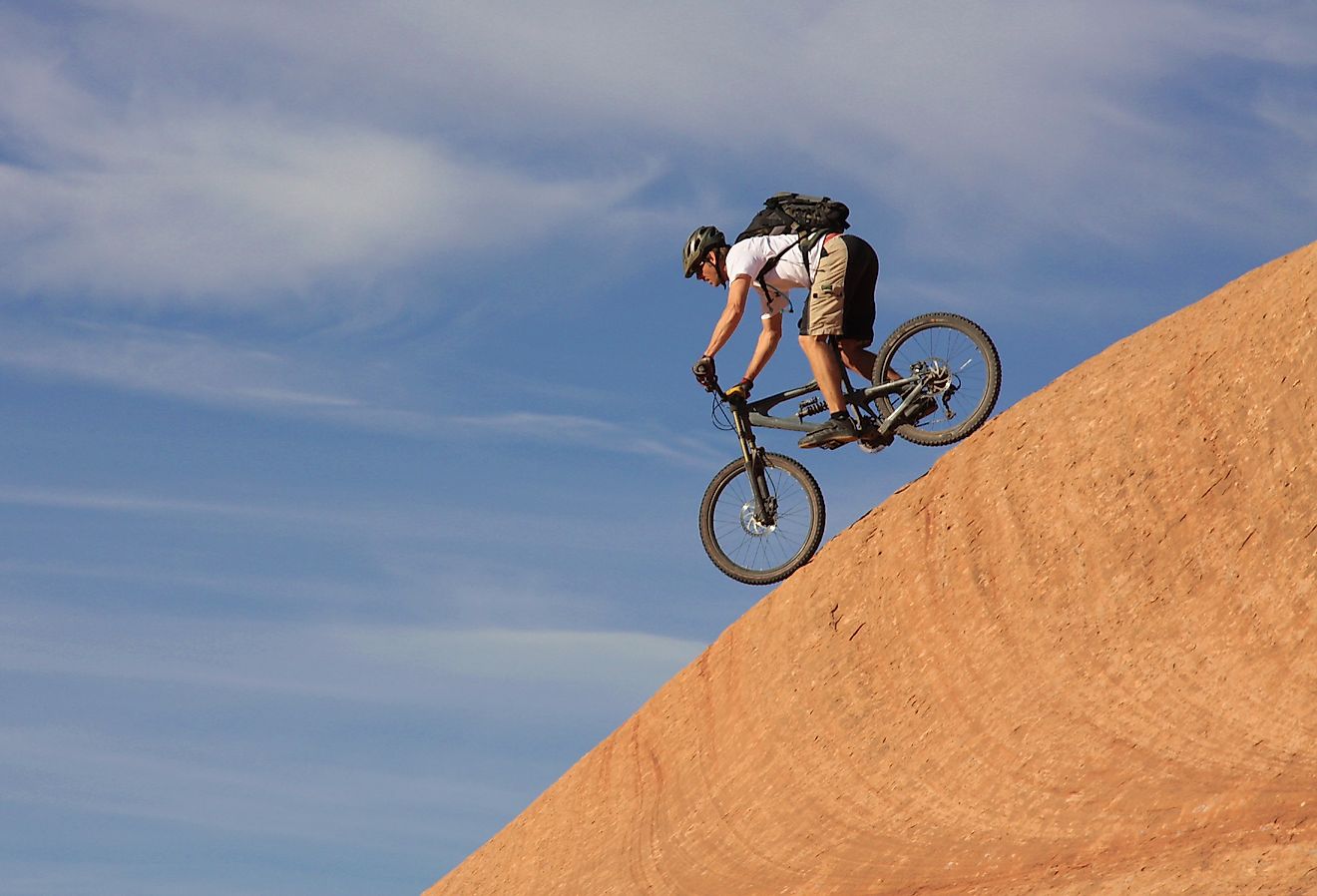 A fearless mountain biker drops down a steep section of Moab's Slickrock Trail, Utah.