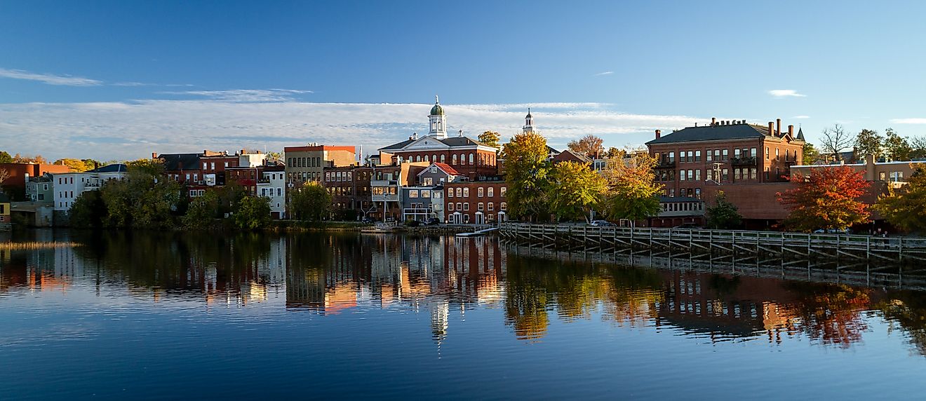 The riverfront buildings of Exeter, New Hampshire, reflected in the calm waters of the river.