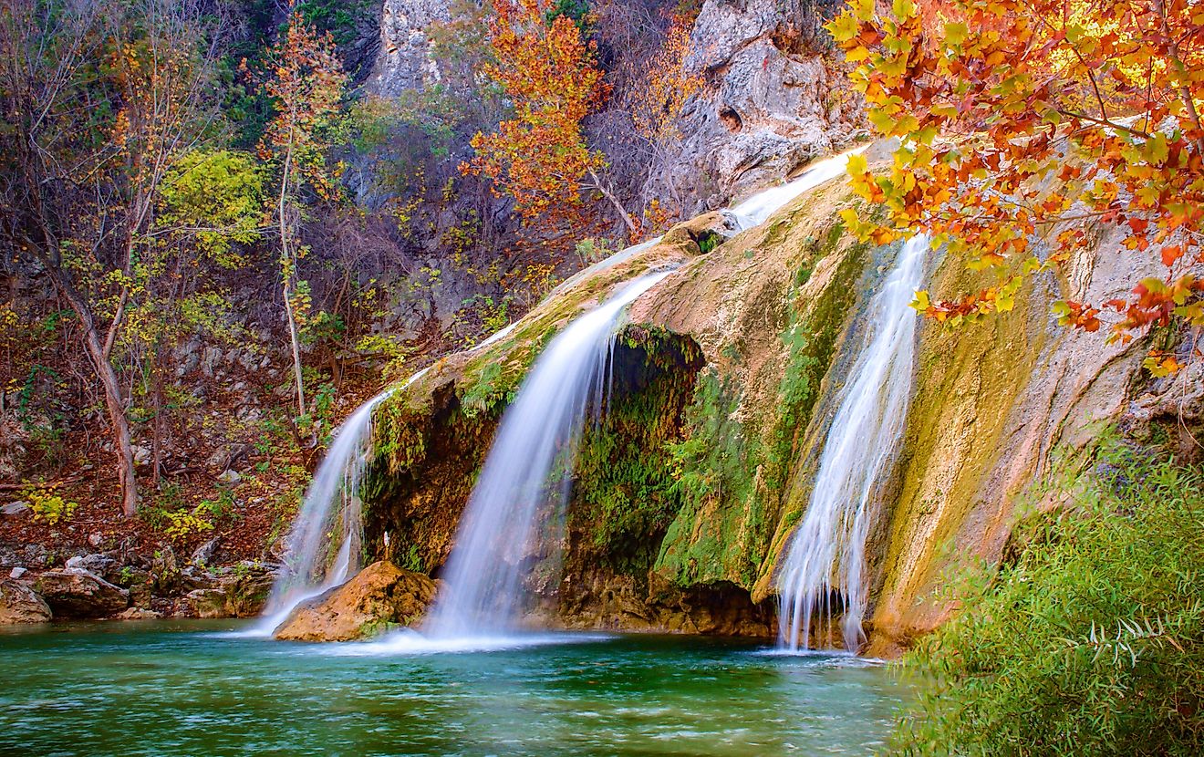 Turner Falls waterfall near Davis, Oklahoma, surrounded by vibrant fall foliage in shades of red, orange, and yellow.