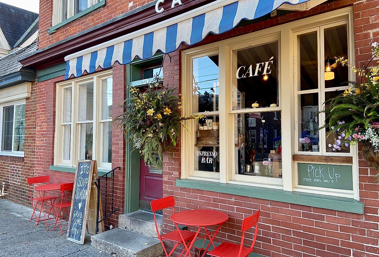 Exterior of a cafe with a striped awning and red tables and chairs in downtown Stroudsburg, Pennsylvania. Image credit Here Now via Shutterstock.