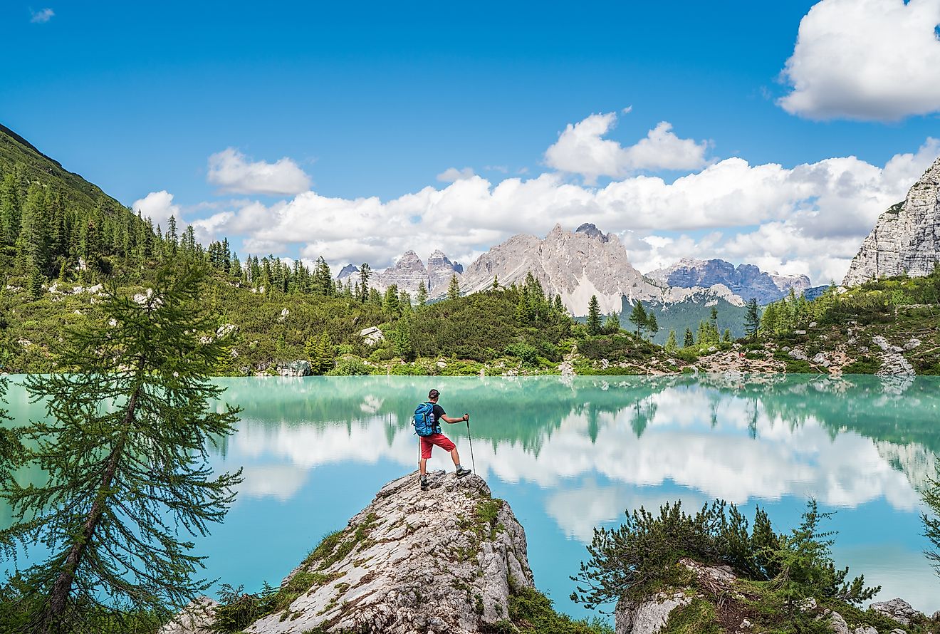 Backpacker with backpack enjoying the turquoise Lago di Sorapiss 1,925m altitude (mountain lake) view as he has mountain walk in Dolomite Mountains, Italy. Active people in nature concept.