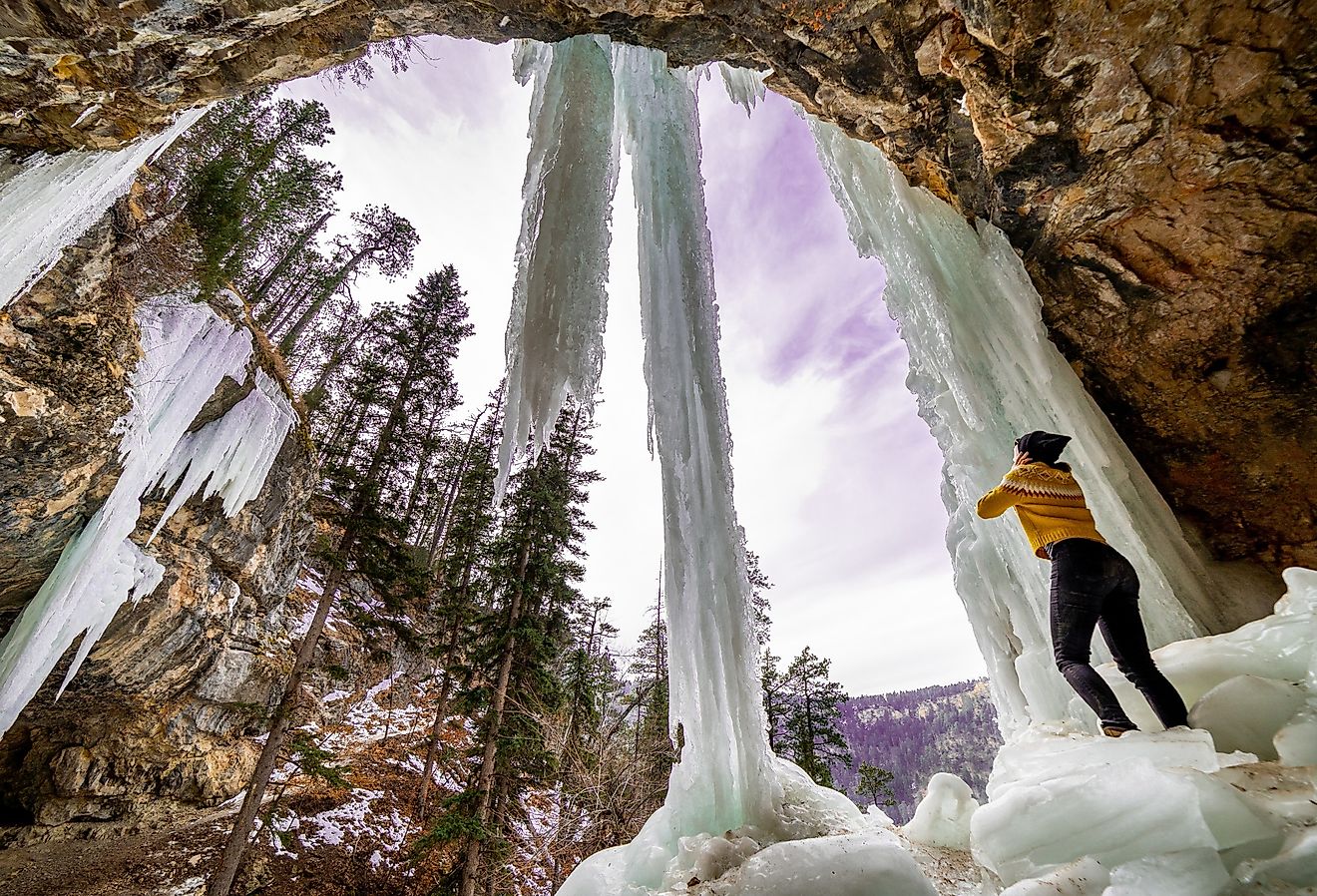 Girl standing under frozen waterfall in Spearfish, South Dakota.