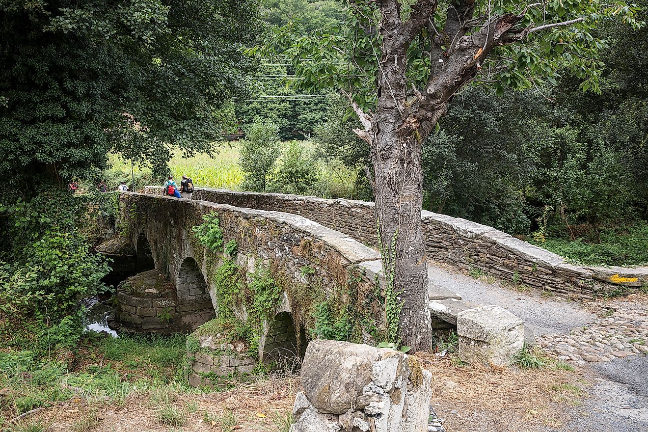 Pilgrims on the Ponte Áspera medieval bridge over Pequeño River, Sarria, Spain.