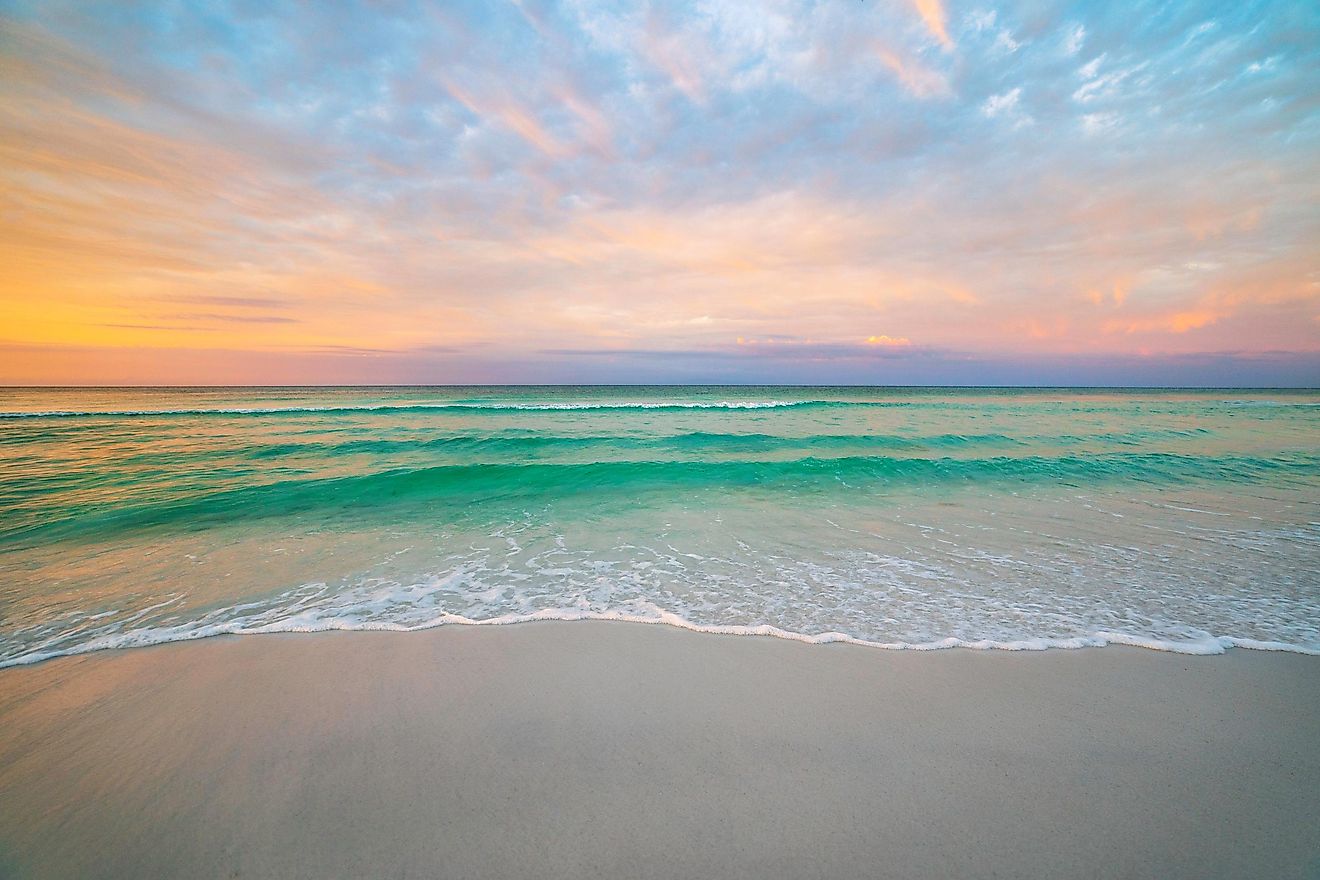 Morning sunrise casting a warm glow over Destin, Florida, with the skyline silhouetted against the brightening sky.