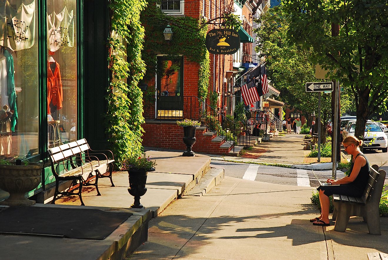  A young woman works on a laptop sitting on a bench in downtown Cold Spring, New York, via James Kirkikis / iStock.com