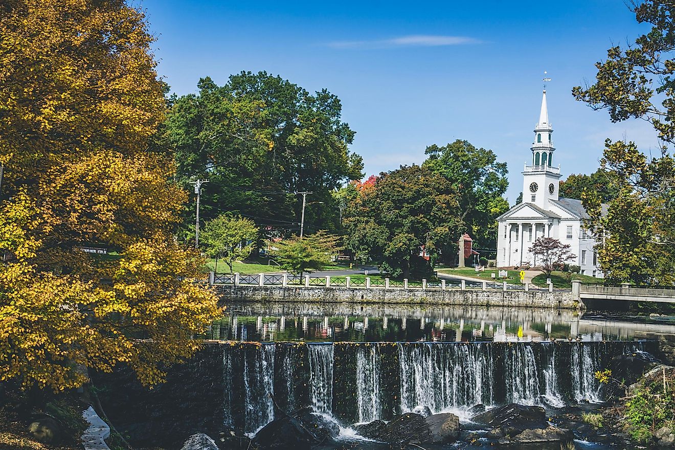 View of white church and waterfall surrounded by trees in Milford, Connecticut