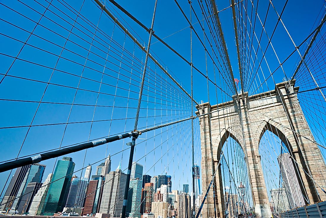 The buildings of New York peak out behind the Brooklyn Bridge. 