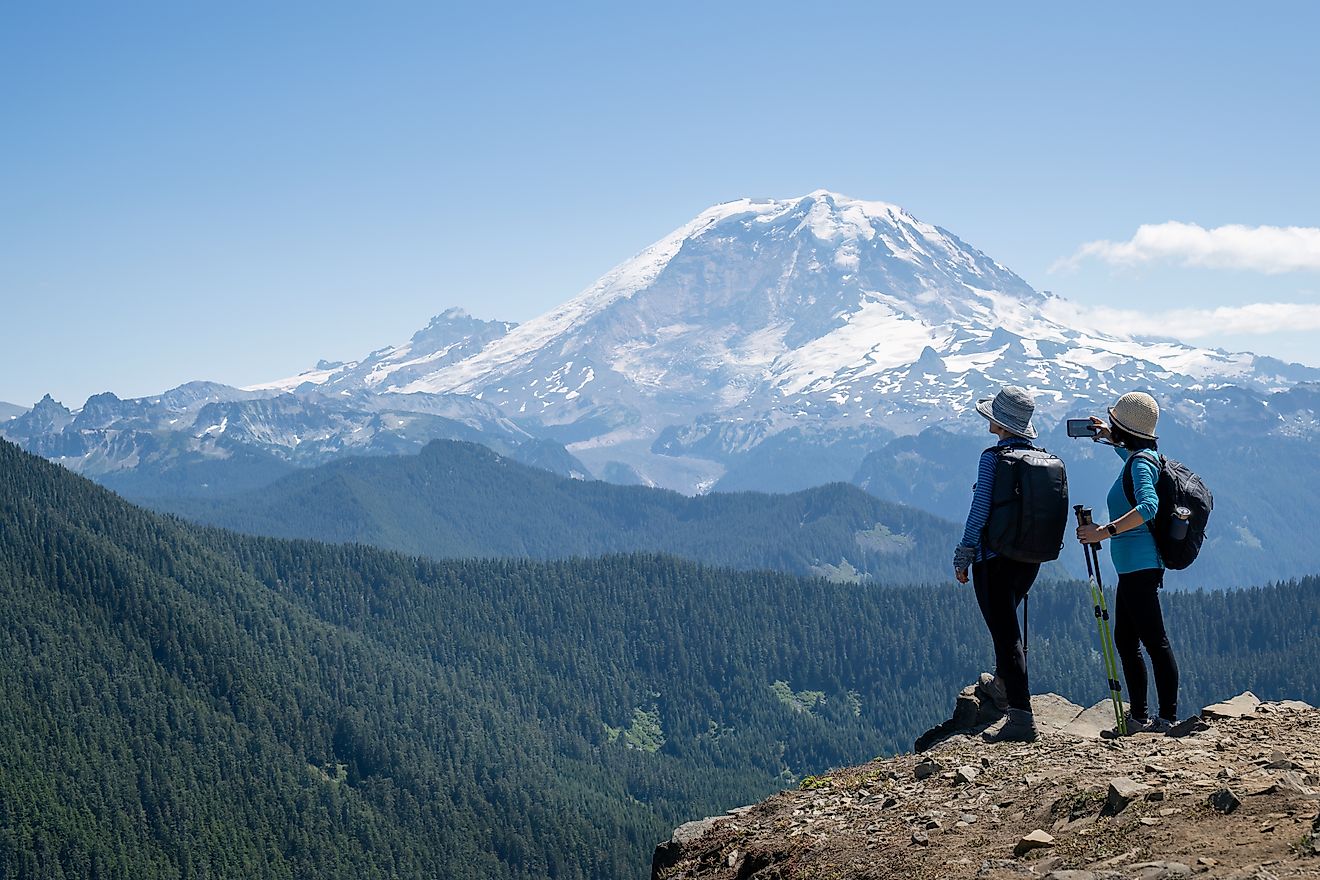 Hikers pause to take photos of Mount Rainier and the surrounding countryside.