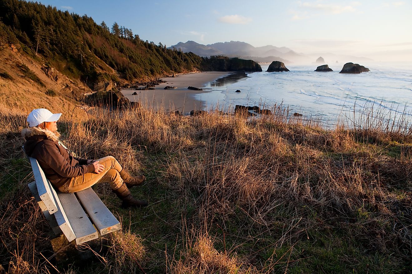 woman sitting on a bench enjoying the scenic view of the Oregon Coast by Cannon Beach