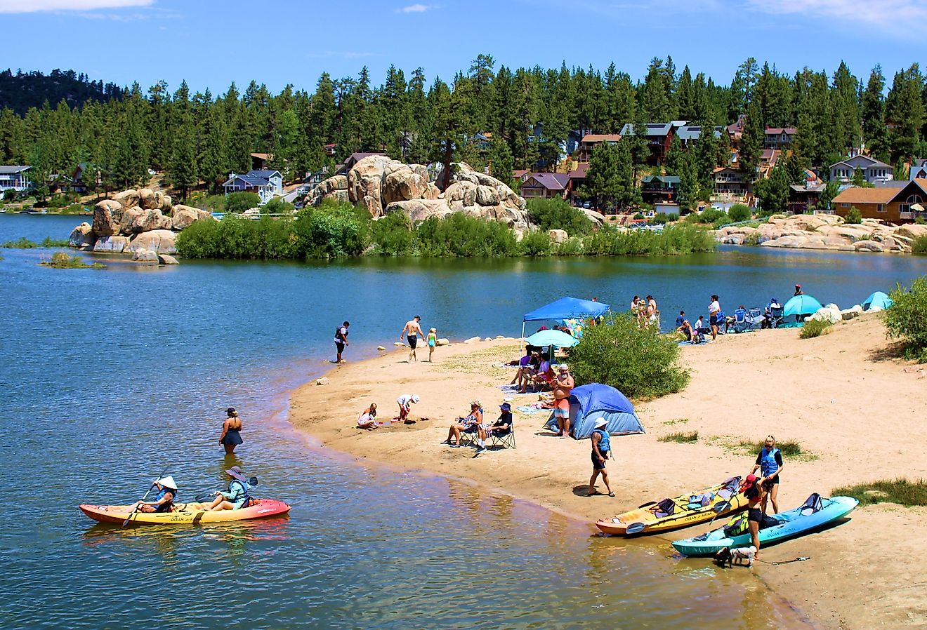 People kayaking besides a sandy beach cove in Big Bear Lake, California. Image credit photojohn830 via Shutterstock