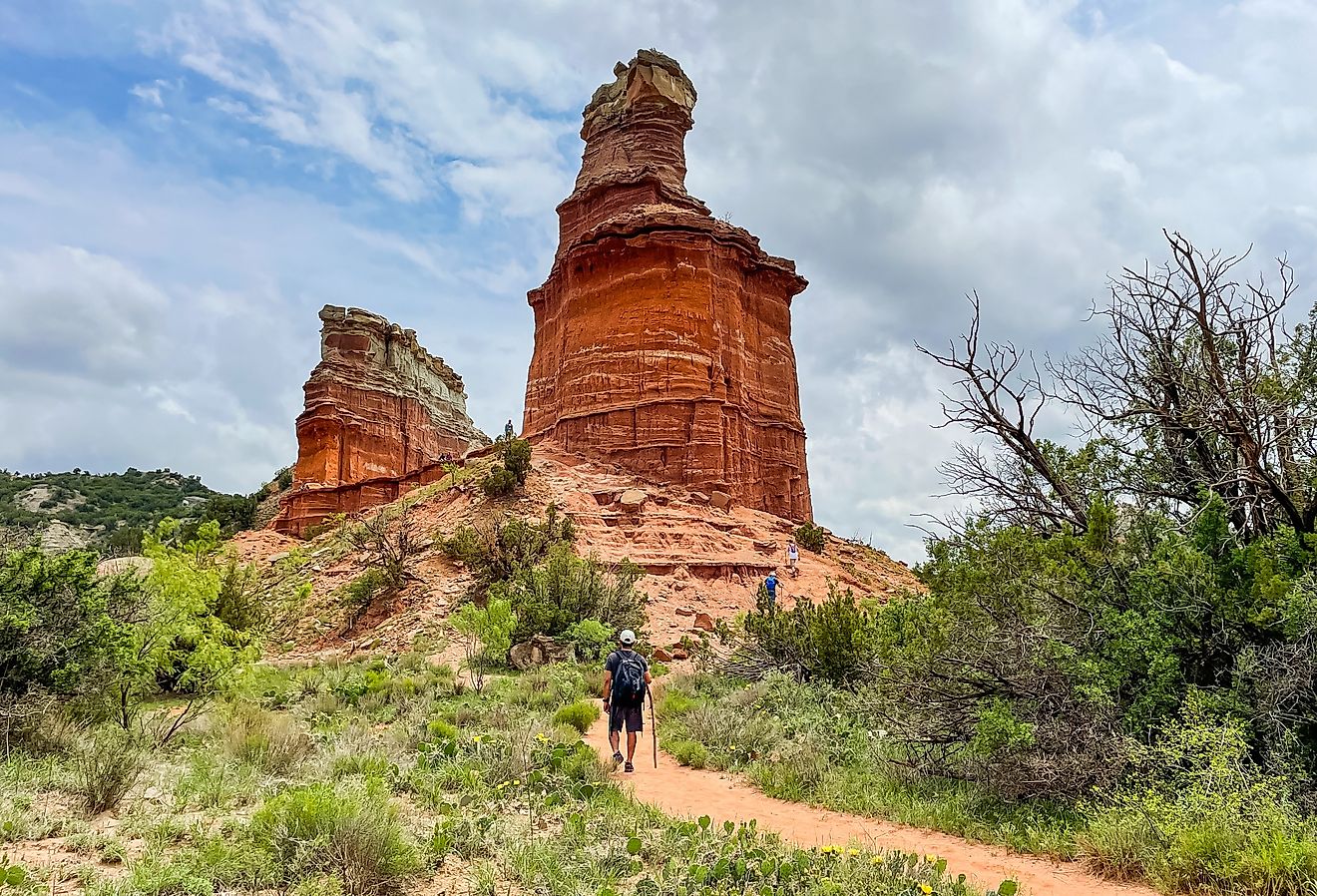 Lighthouse symbol rock with visitors walking towards it in Palo Duro Canyon State Park, Texas.