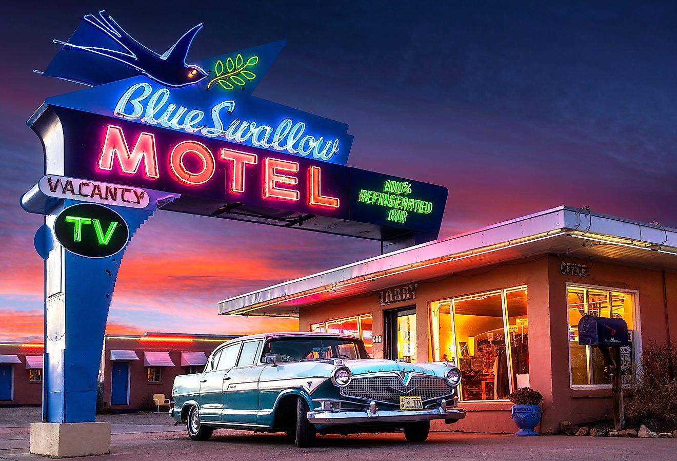 Historic Blue Swallow Motel on Route 66 with neon and classic car at sunset in Tucumcari via Shutterstock.