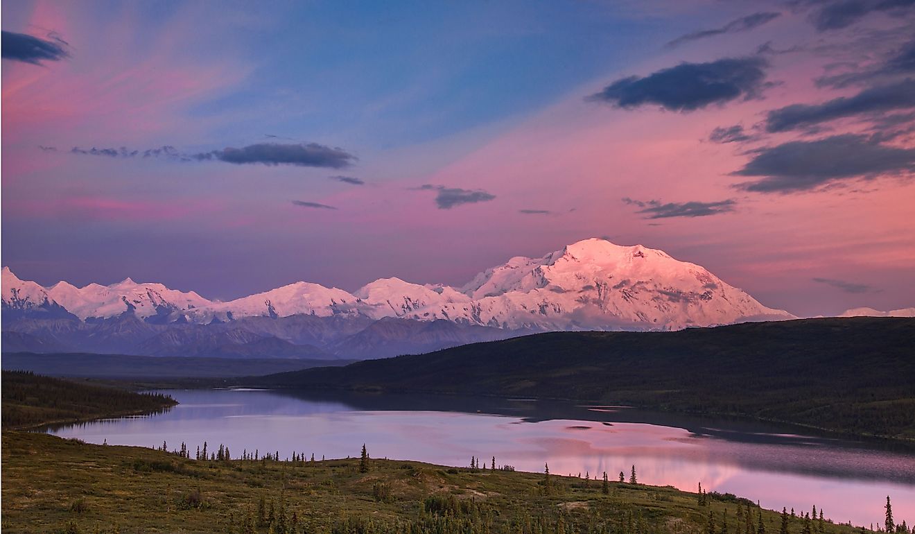 Alaska's mount denali looms behind wonder lake at colorful sunset with alpenglow.