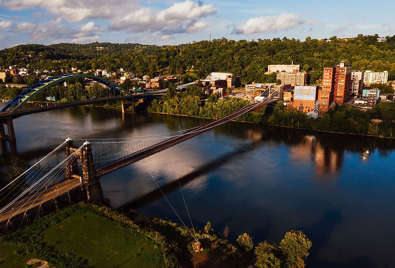 Aerial view of the historic Wheeling Suspension Bridge that carries the National Road over the still blue waters of the Ohio River in Wheeling, West Virginia.