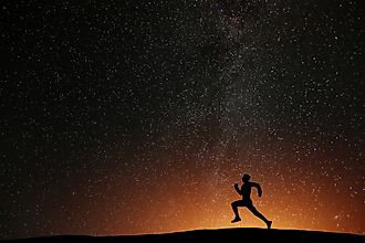 Runner athlete running on the hill with beautiful starry night background.